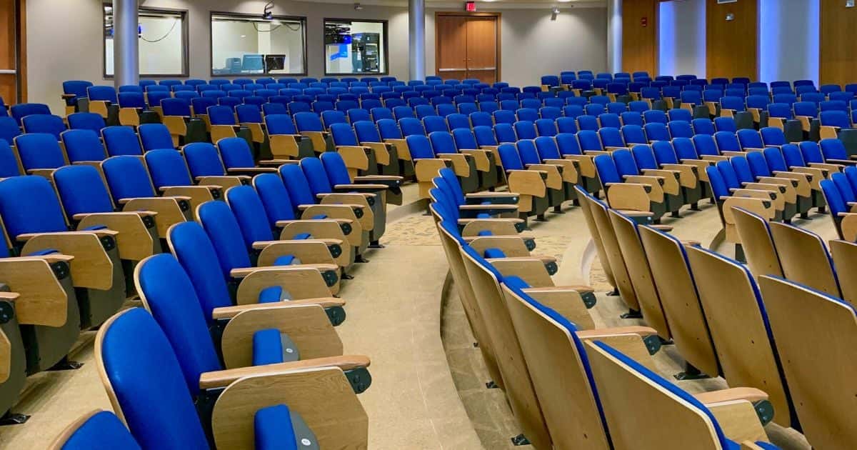 Installed fixed auditorium seating with wood back panels and tablet arms in a tiered venue