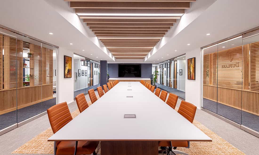 Long executive conference table with leather chairs in a modern boardroom with wood-slat walls