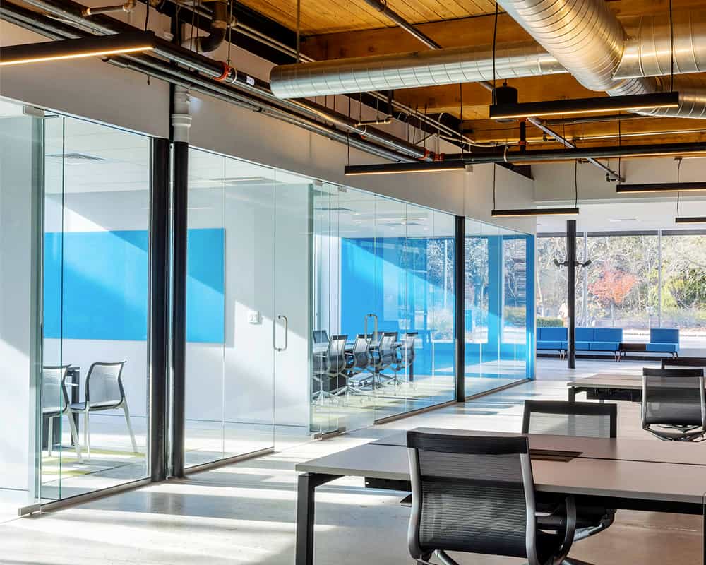 Bright loft office with a vivid blue Clarus glassboard in a glass-walled meeting room