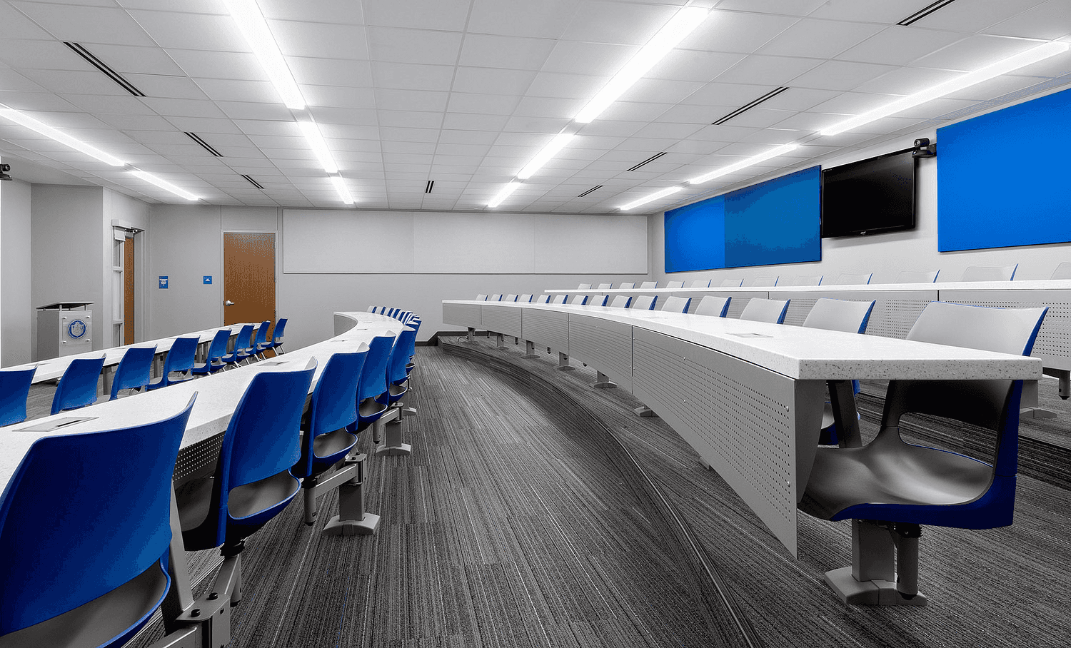 Modern lecture hall with tiered seating, integrated desk surfaces, and AV presenter station in a Florida university