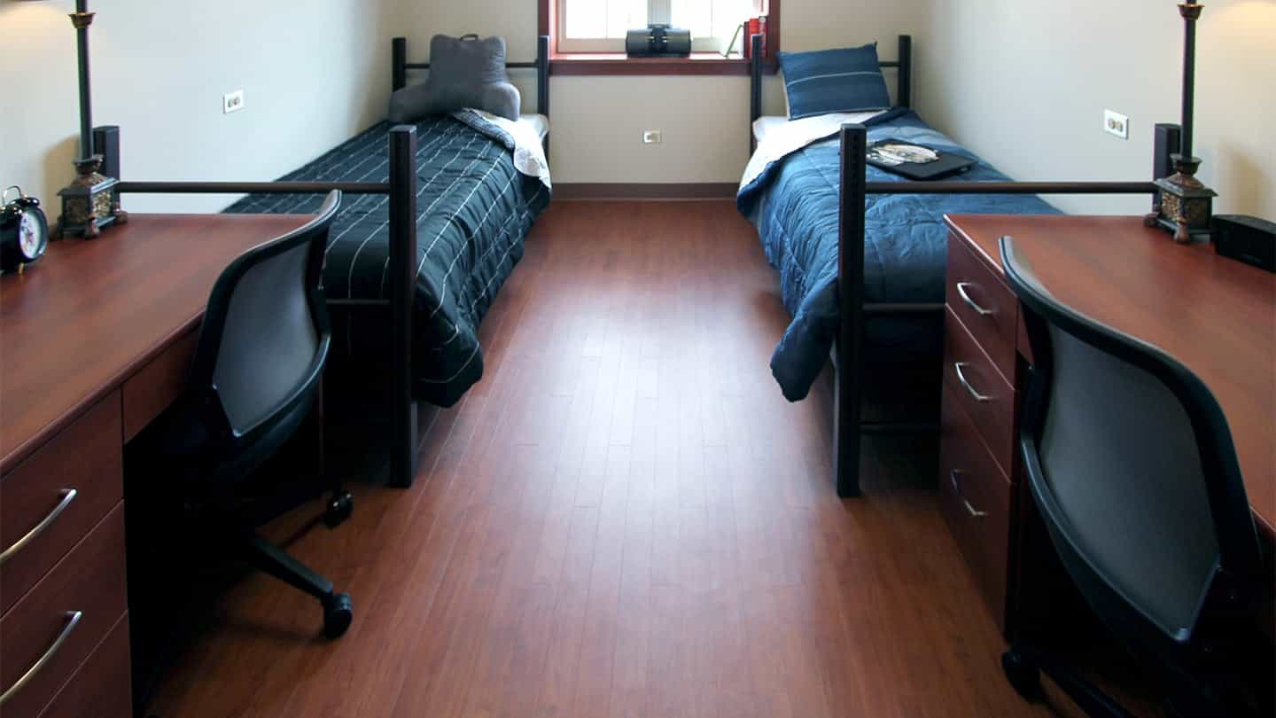 Furnished university dorm room with two beds, desks, and task chairs at Northern Illinois University