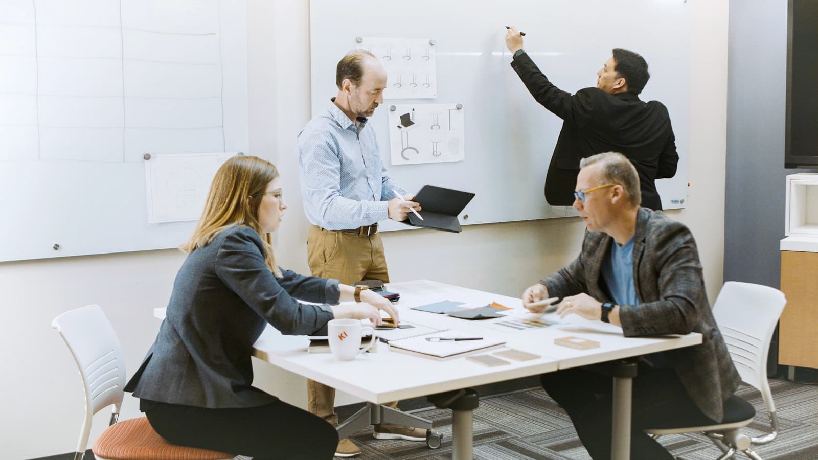 Design team reviewing furniture layout sketches and material swatches during a space planning session